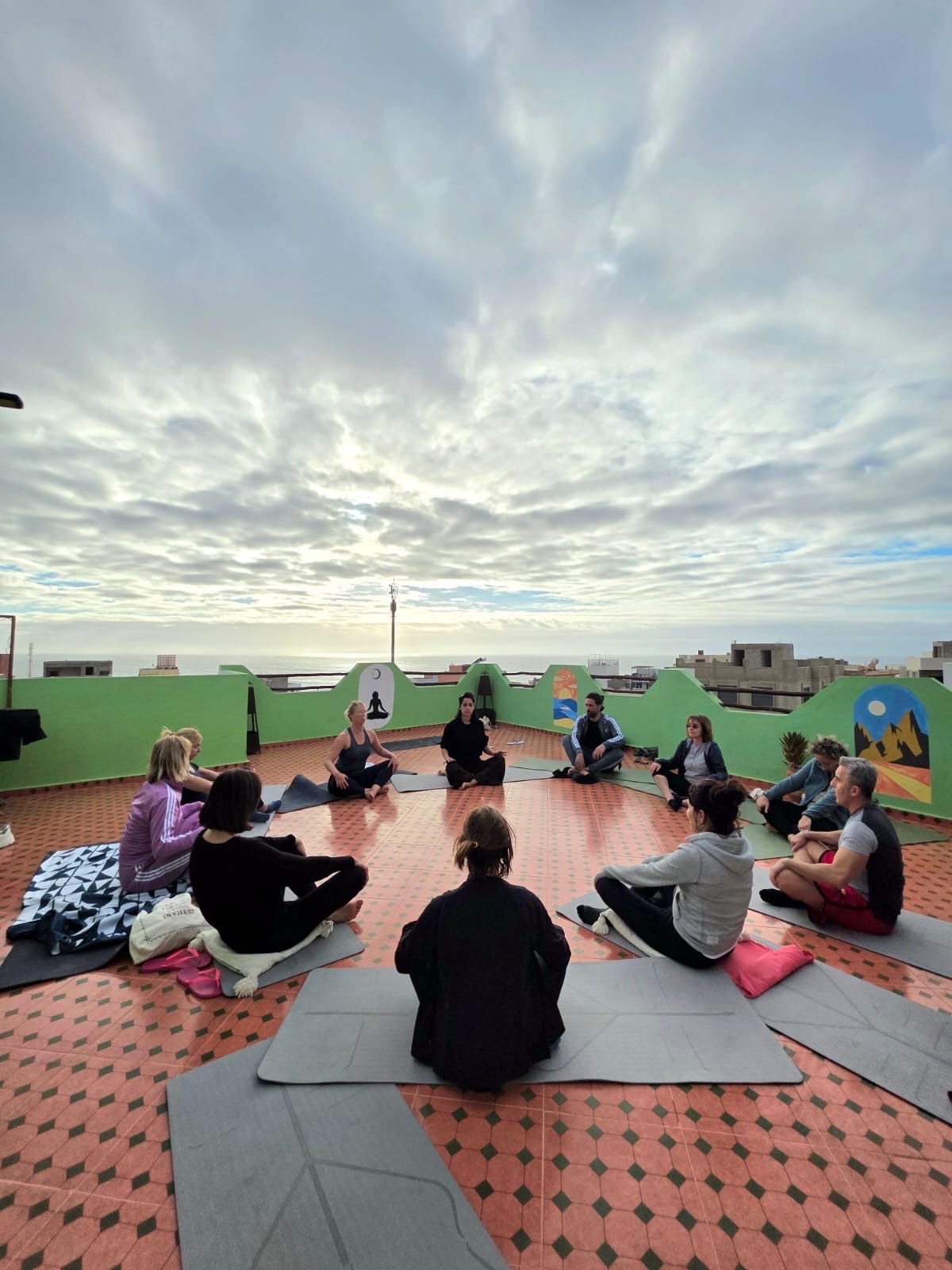 Groupe de yoga sur la terrasse rooftop de Dar Mouja avec vue sur la mer